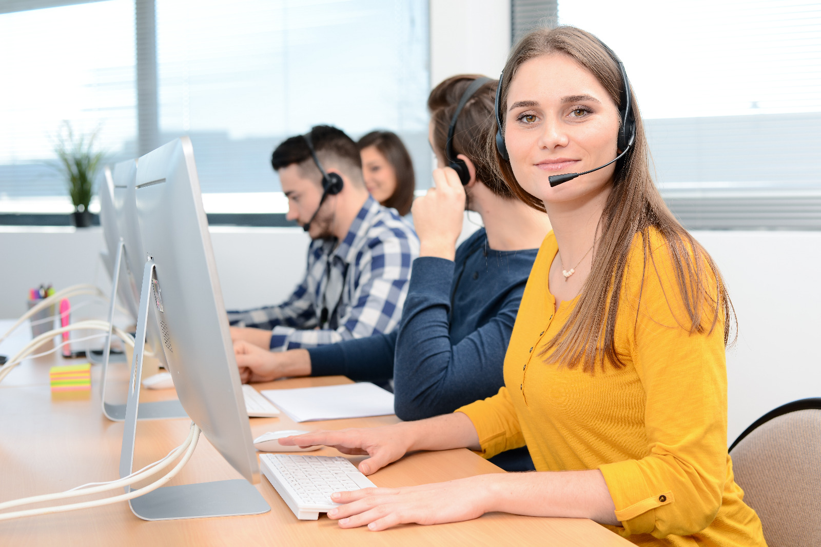 Customer support team taking calls about Worktop Refinishing in Gants Hill, seated at computers in a bright office with a light-coloured smooth hard floor surface.