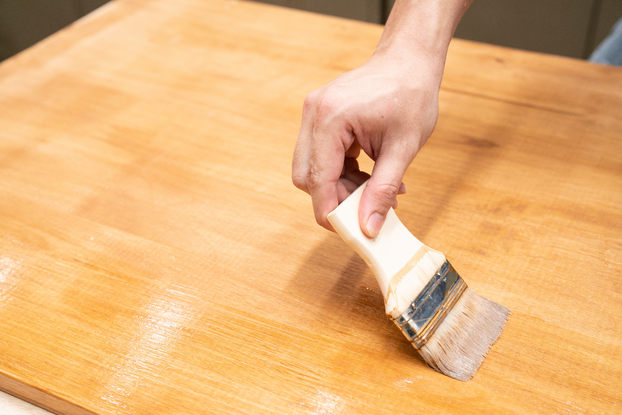 Worktop Refinishing in Gants Hill on a solid oak kitchen worktop, with a hand applying protective finish to the smooth timber surface.