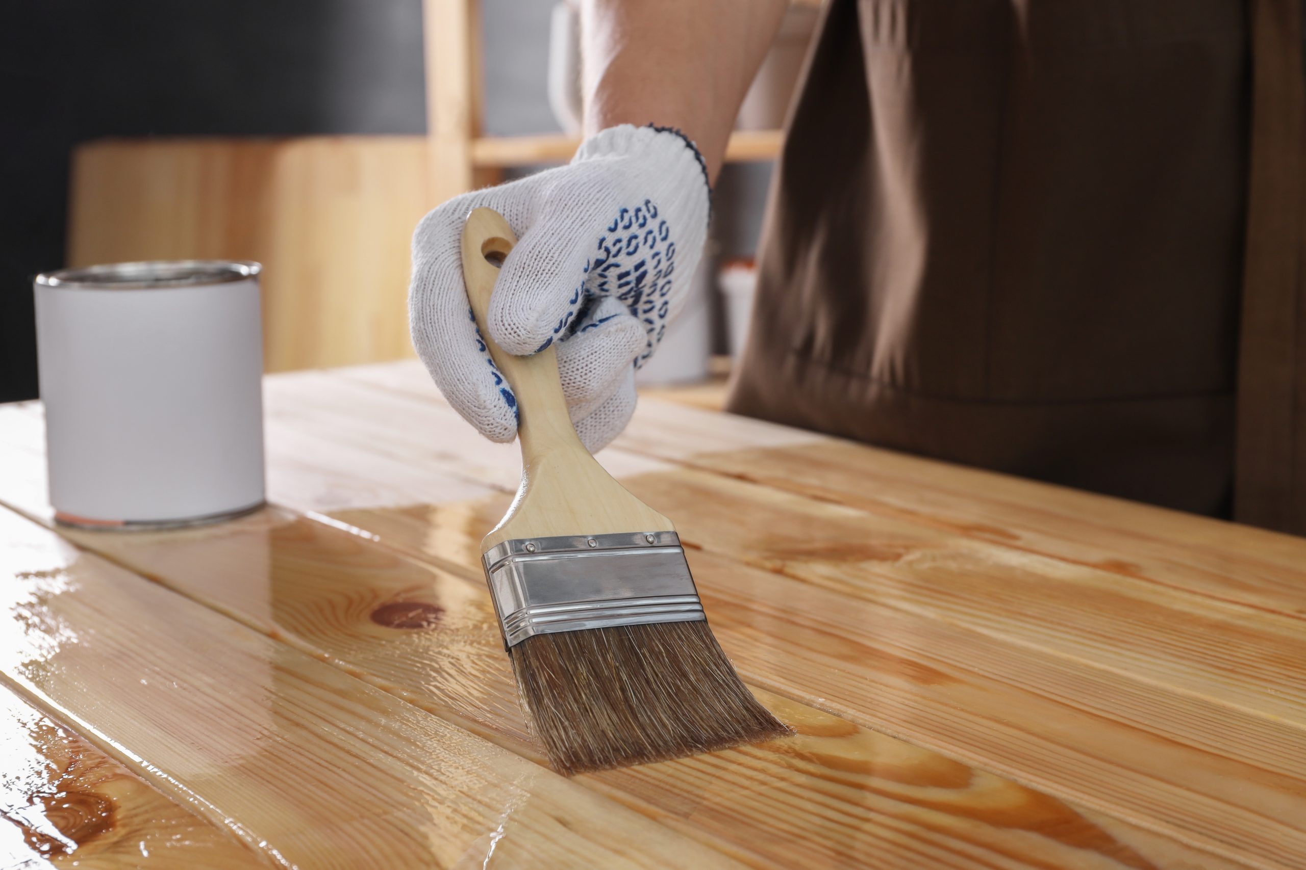Worktop Refinishing in Gants Hill on a solid pine plank wooden worktop surface, with a tradesperson in gloves brushing on a fresh protective finish.